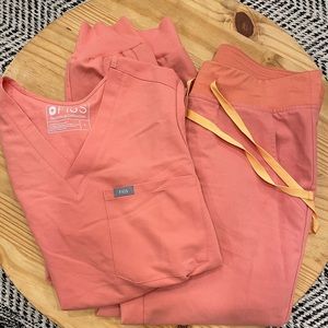 Figs scrubs set in coral with orange tie.